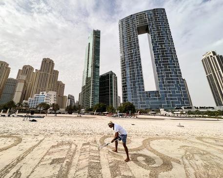 یک هنرمند در دوبی در حال ترسیم تابلوی شنی+عکس