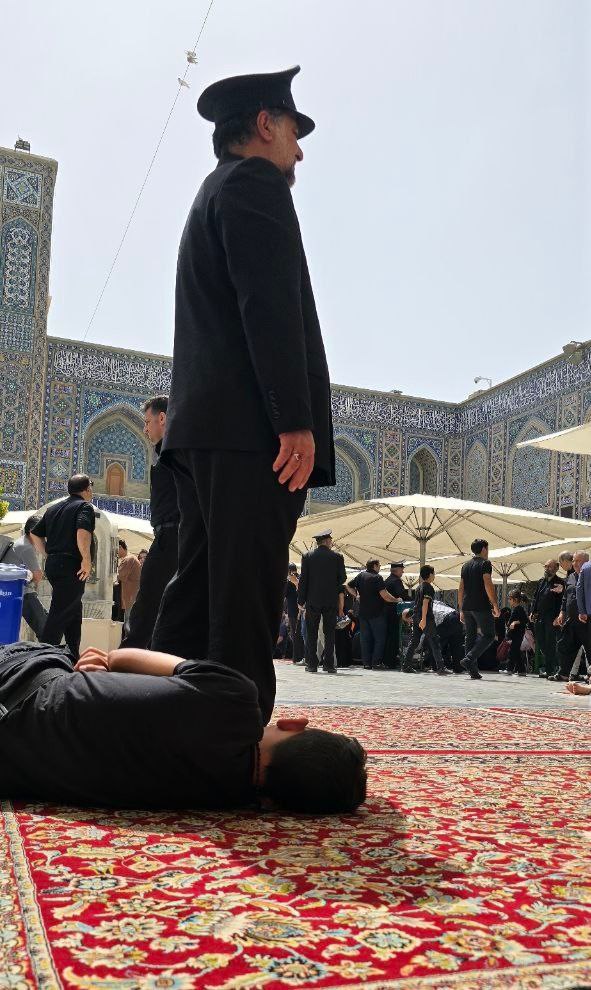 خادمی که بالای سر زائرامام رئوف  ایستاده تا نور خورشید او را اذیت نکند